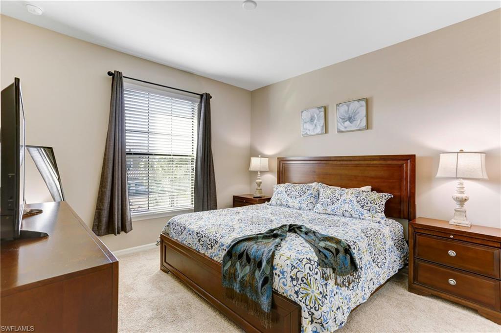 9433 Benvenuto Court, Unit 201 Naples, FL 34119 - Photo 16 of 32 a bedroom with a bed and a flat tv screen on a dresser
