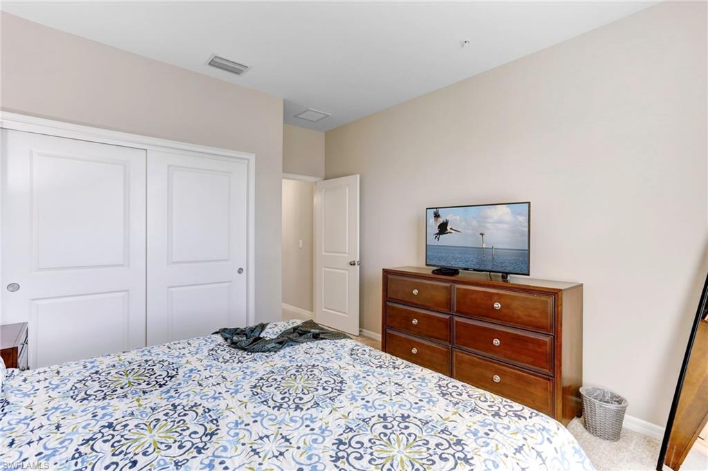 9433 Benvenuto Court, Unit 201 Naples, FL 34119 - Photo 17 of 32 a bedroom with a bed and a dresser in it