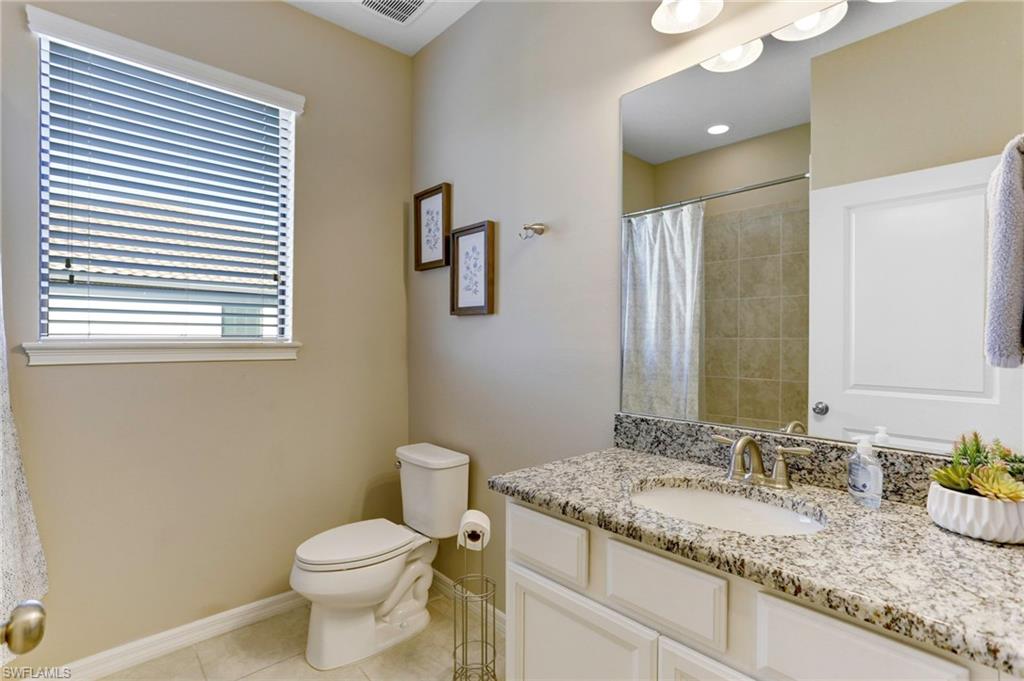 9433 Benvenuto Court, Unit 201 Naples, FL 34119 - Photo 18 of 32 a bathroom with a granite countertop sink toilet and mirror