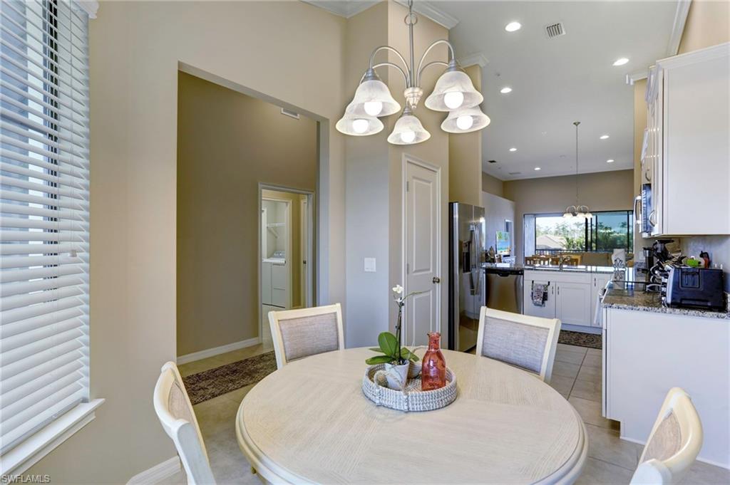 9433 Benvenuto Court, Unit 201 Naples, FL 34119 - Photo 6 of 32 a dining room with wooden floor a chandelier a glass table and chairs