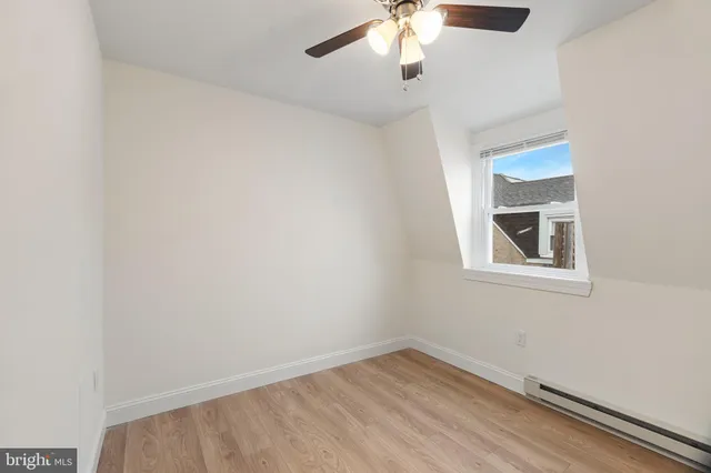 an empty room with a window and chandelier fan