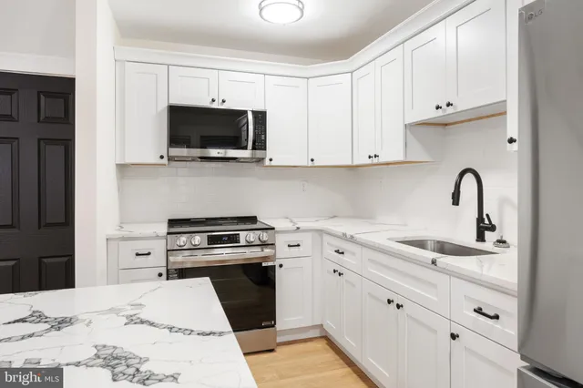 a kitchen with white cabinets and stainless steel appliances