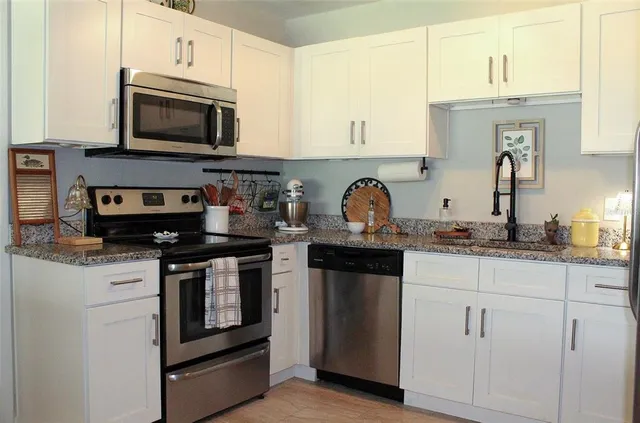 a kitchen with stainless steel appliances granite countertop a stove a sink and a microwave