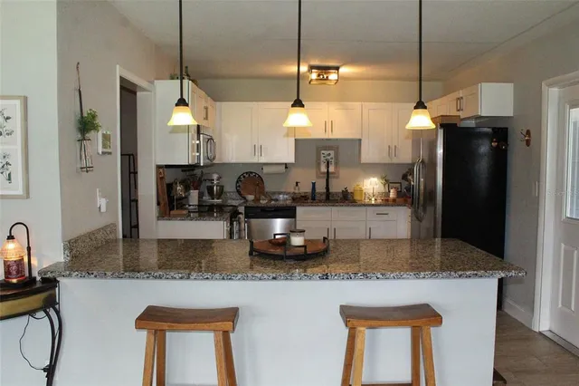 a kitchen with stainless steel appliances granite countertop a sink a refrigerator and a granite counter tops