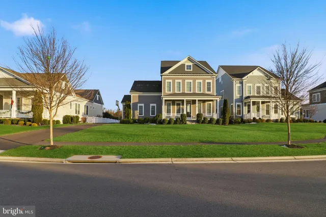 a view of a white house next to a yard with big trees