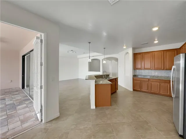 a kitchen with stainless steel appliances kitchen island granite countertop a refrigerator and a stove top oven