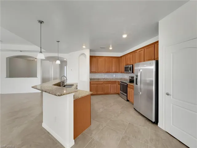 a kitchen with stainless steel appliances kitchen island granite countertop a refrigerator a sink a stove and a cabinets