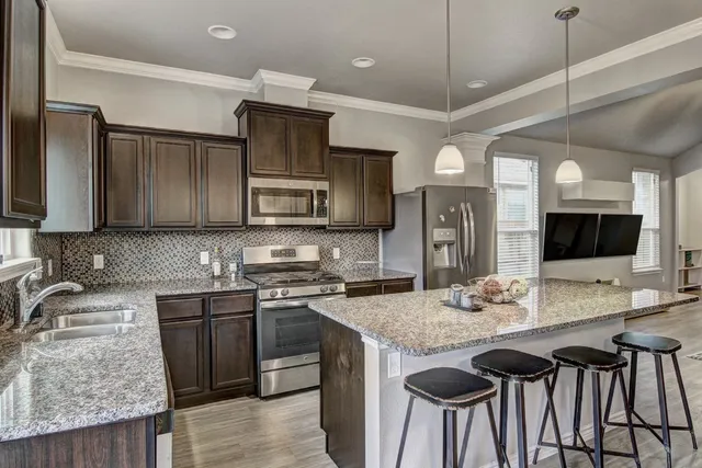 a kitchen with granite countertop a sink stove and microwave