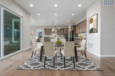 a dining room with kitchen island a dining table wooden floor and a view of kitchen