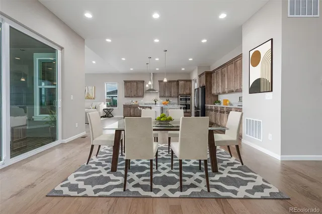 a dining room with kitchen island a dining table wooden floor and a view of kitchen