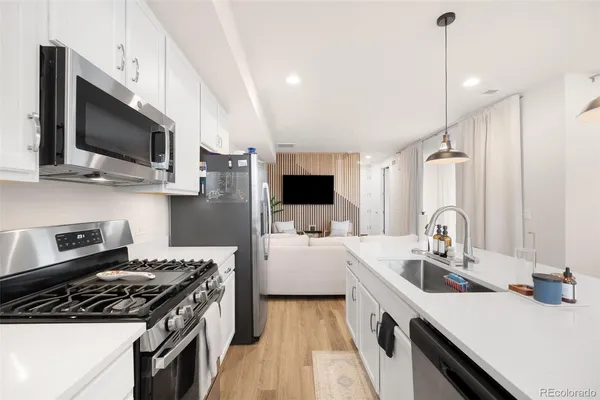 a kitchen with stainless steel appliances a sink dishwasher a stove top oven a refrigerator with wooden floor and cabinets