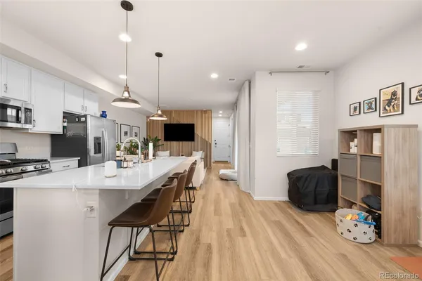 a kitchen with stainless steel appliances kitchen island granite countertop a refrigerator a stove a microwave oven a dining table and chairs with wooden floor