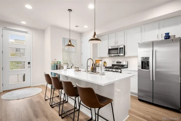 a kitchen with kitchen island a dining table chairs stainless steel appliances and cabinets