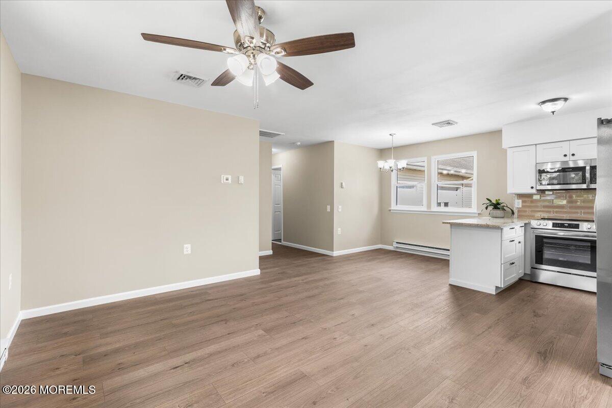 16 D Spring Street, Unit 50 Whiting, NJ 08759 - Photo 10 of 28 a view of a kitchen with a stove cabinets wooden floor and a ceiling fan