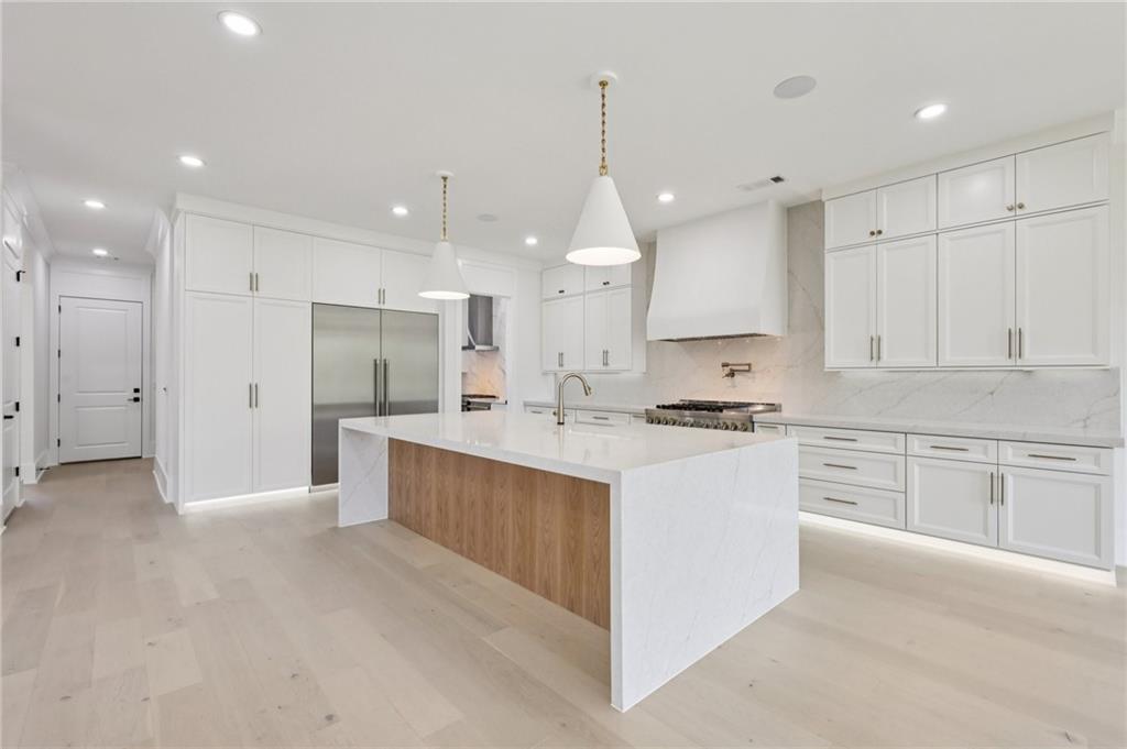 2395 Kilgore Road Buford, GA 30519 - Photo 15 of 68 a large kitchen with stainless steel appliances kitchen island granite countertop a stove a sink a refrigerator and white cabinets with wooden floor