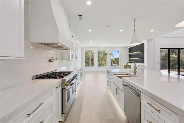 a kitchen with stainless steel appliances granite countertop a sink and cabinets with wooden floor