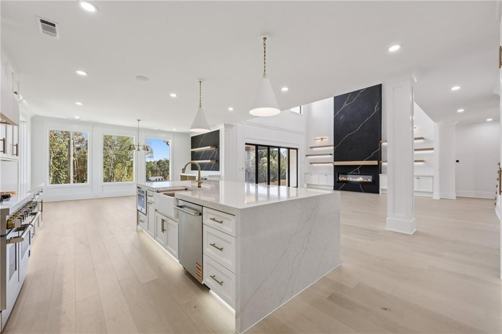 2395 Kilgore Road Buford, GA 30519 - Photo 19 of 68 a large kitchen with stainless steel appliances a large counter top a stove a chimney a sink and a refrigerator