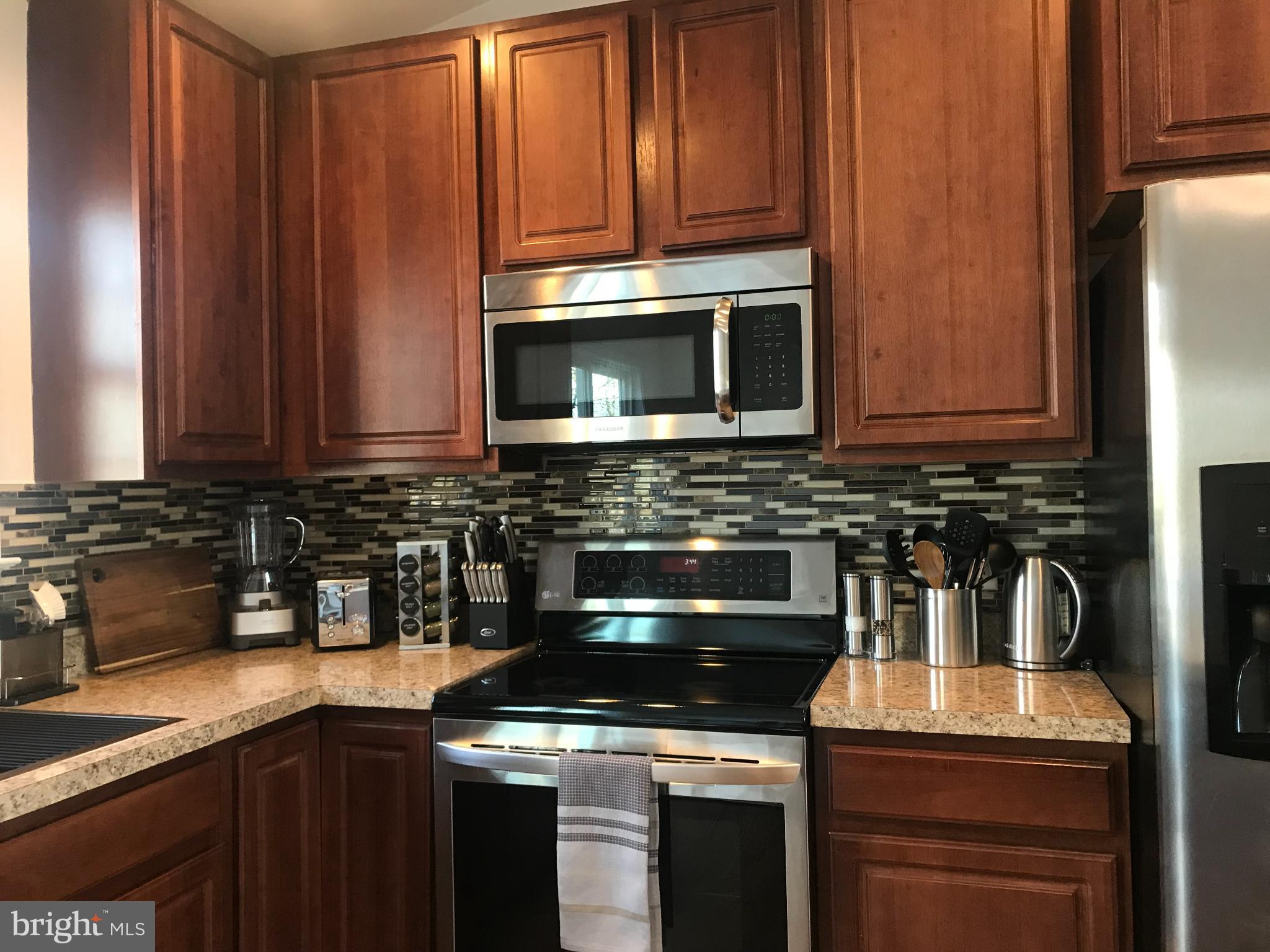1221 Cox Neck Road Chester, MD 21619 - Photo 9 of 35 a kitchen with granite countertop a stove top oven microwave and cabinets