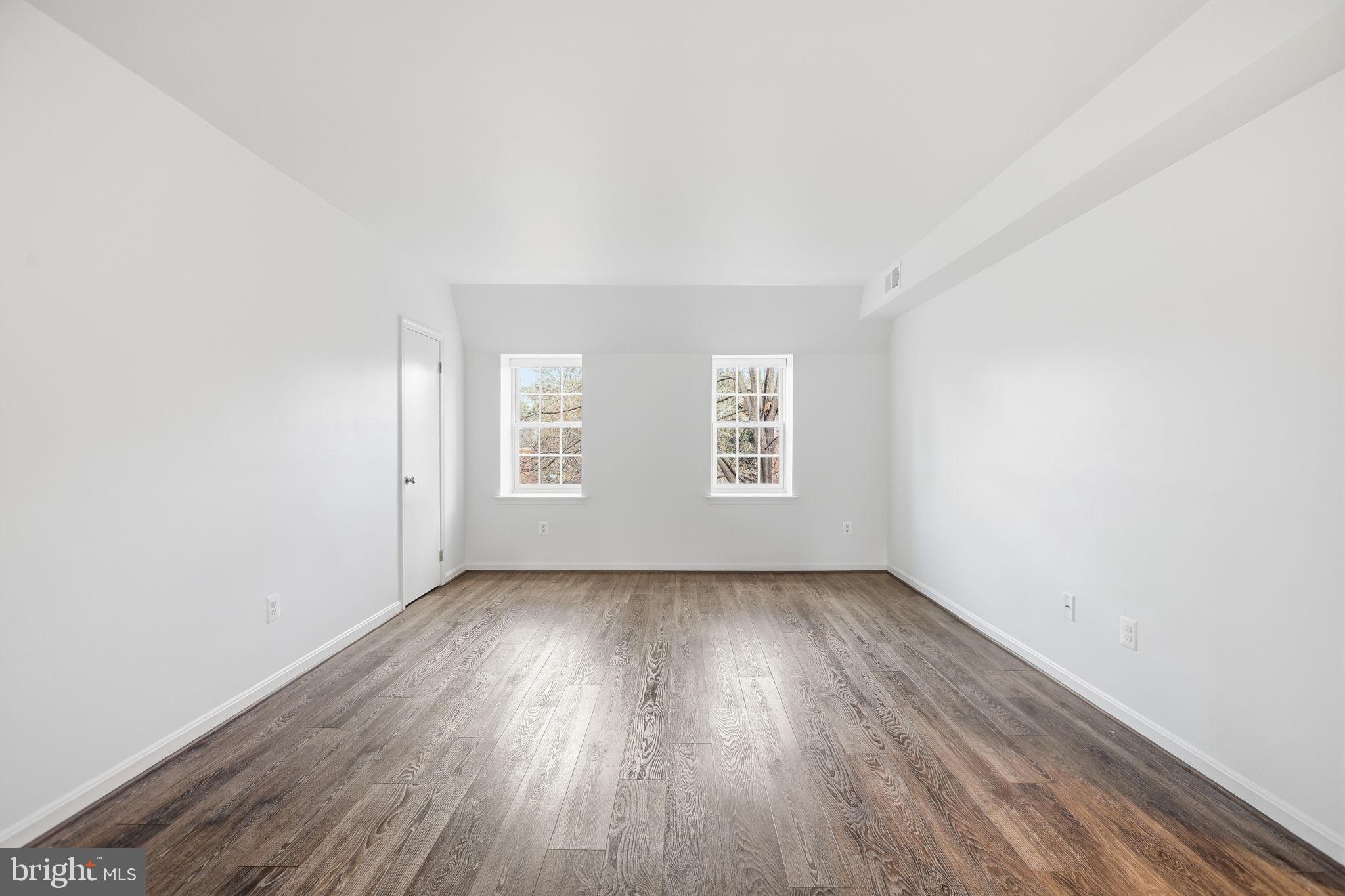 1744 North Rhodes Street, Unit 310 Arlington, VA 22201 - Photo 14 of 24 an empty room with wooden floor and windows