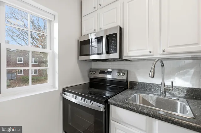 a kitchen with granite countertop a sink stainless steel appliances and cabinets