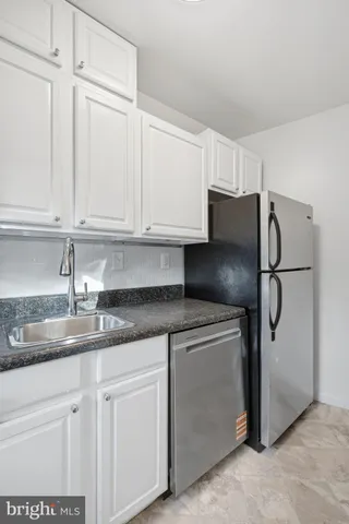 a kitchen with stainless steel appliances granite countertop a refrigerator a sink and white cabinets