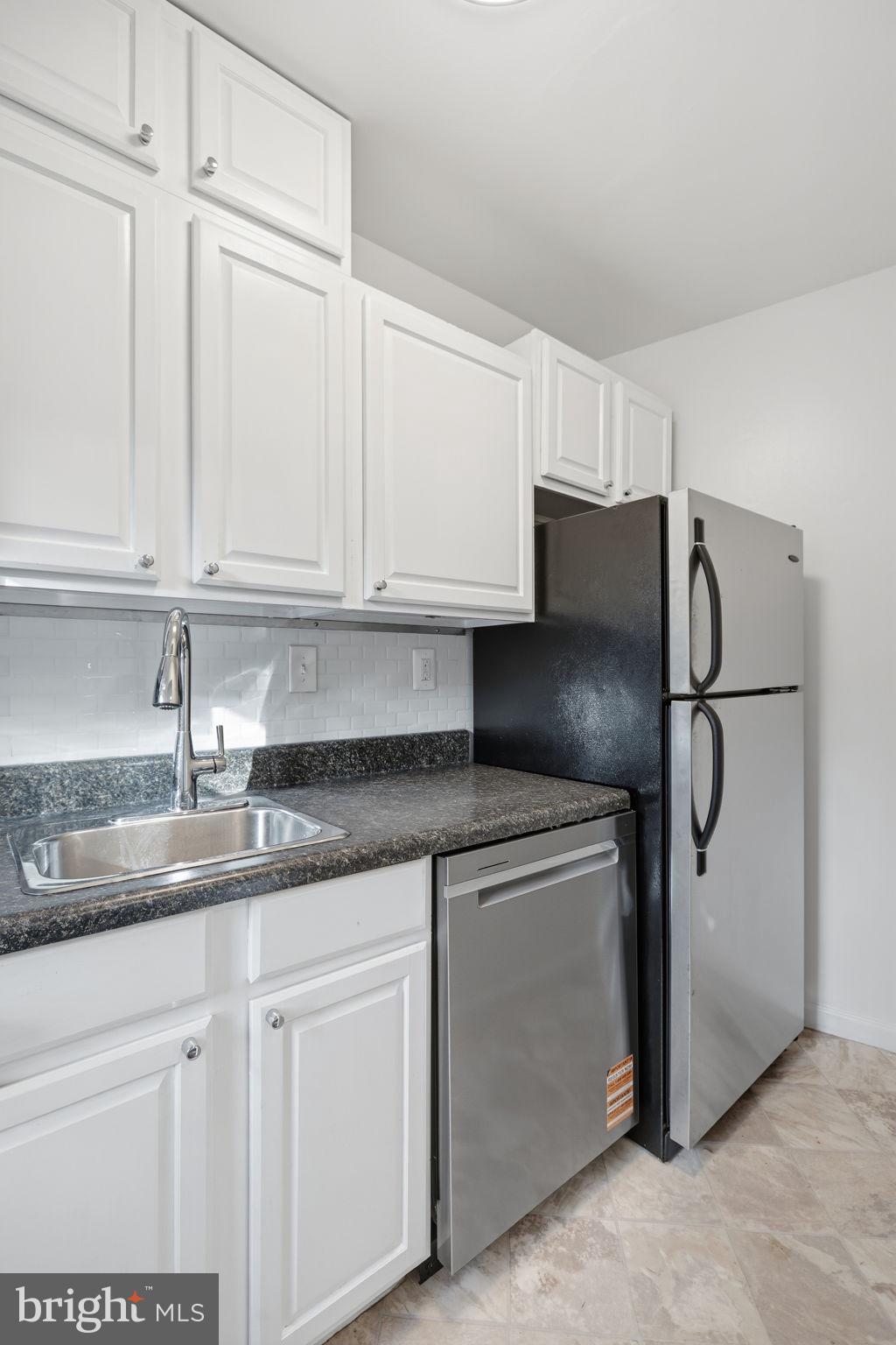 1744 North Rhodes Street, Unit 310 Arlington, VA 22201 - Photo 9 of 24 a kitchen with stainless steel appliances granite countertop a refrigerator a sink and white cabinets
