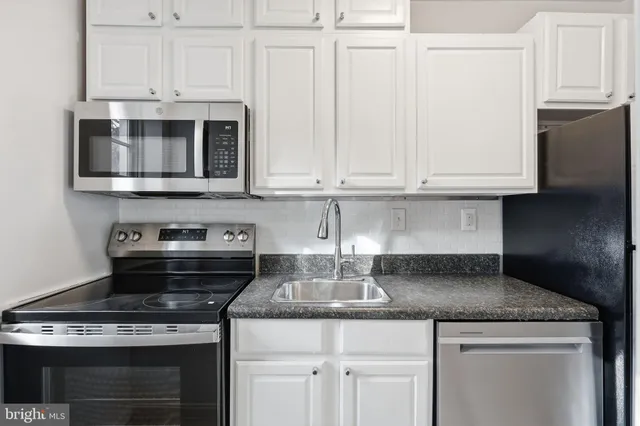a kitchen with granite countertop white cabinets and stainless steel appliances