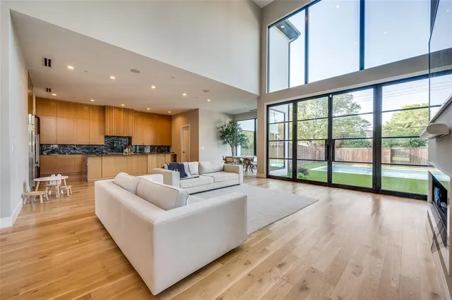 a living room with furniture large windows and wooden floor