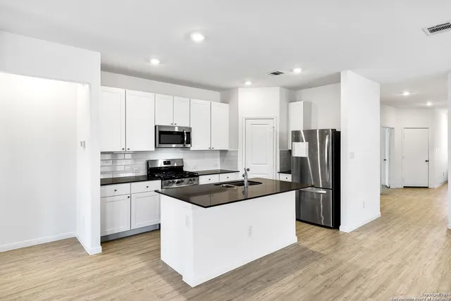a kitchen with granite countertop a refrigerator and a stove top oven