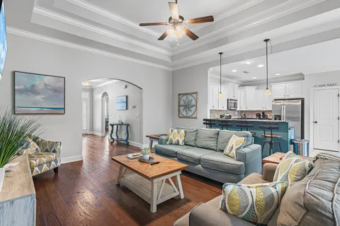 a living room with furniture kitchen view and a chandelier
