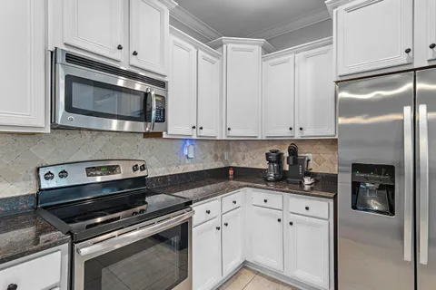 a kitchen with granite countertop white cabinets and stainless steel appliances