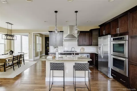 a kitchen with stainless steel appliances granite countertop a stove refrigerator and wooden floor