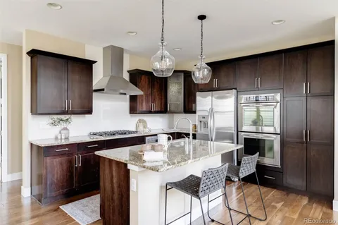 a kitchen with stainless steel appliances granite countertop a sink a stove and a wooden floors