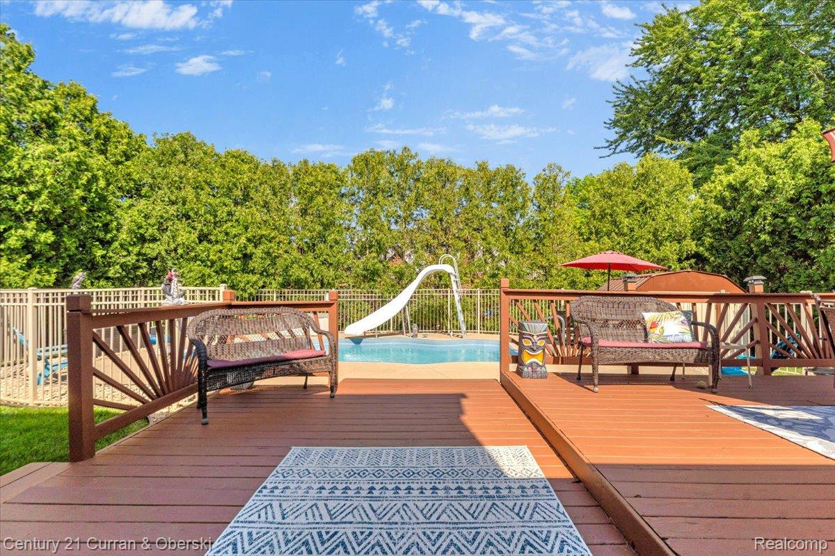 21439 Hall Road Trenton, MI 48183 - Photo 26 of 35 Spacious multi-level wood deck featuring a built-in railing, overlooking a fenced in-ground pool with a waterslide
