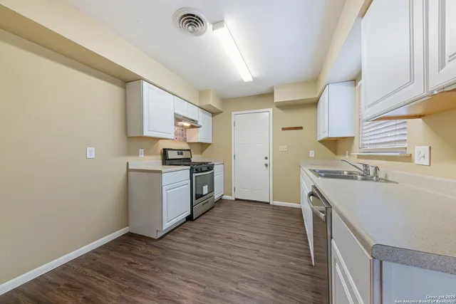 a kitchen with a sink wooden floor and stainless steel appliances