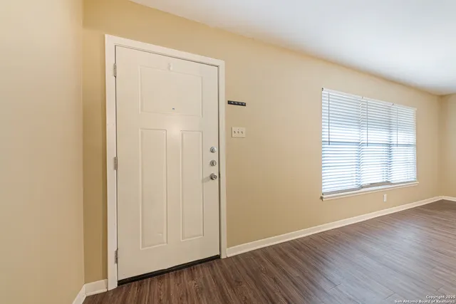 an empty room with wooden floor and window