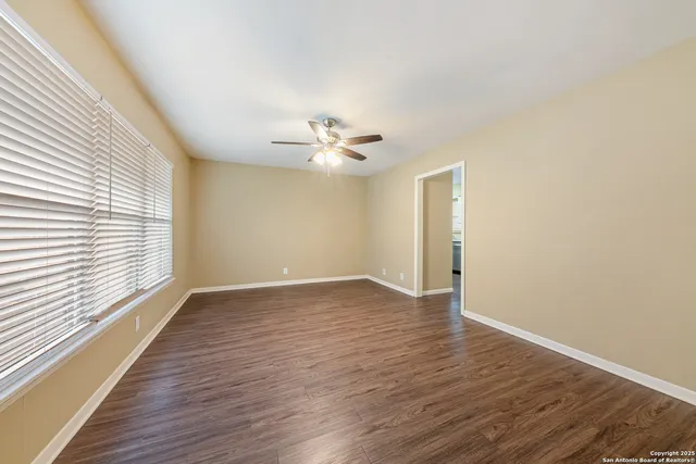 a view of an empty room with wooden floor and a window
