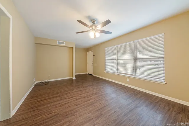 a view of an empty room with a window and wooden floor
