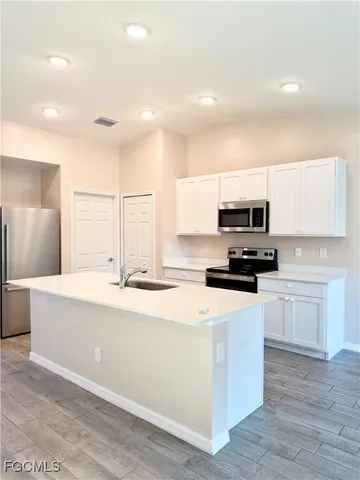 a kitchen with stainless steel appliances a sink a stove a microwave a center island and cabinets