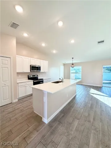 a large white kitchen with kitchen island a stove a sink a refrigerator and cabinets