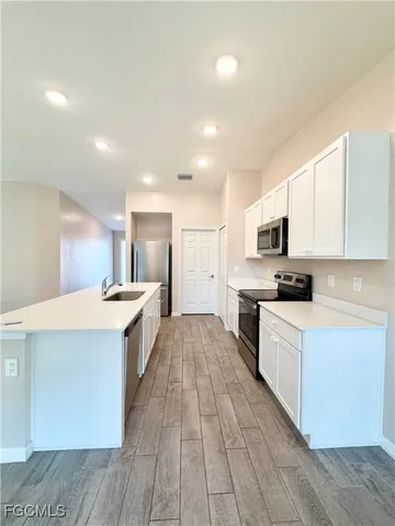 a large kitchen with stainless steel appliances lots of counter space and wooden floor