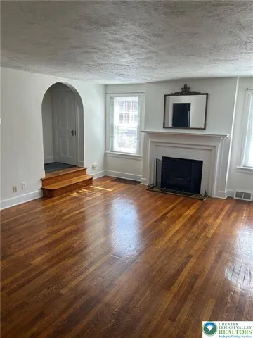 a view of empty room with wooden floor and fireplace