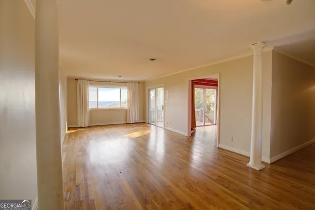a view of an empty room with wooden floor and windows