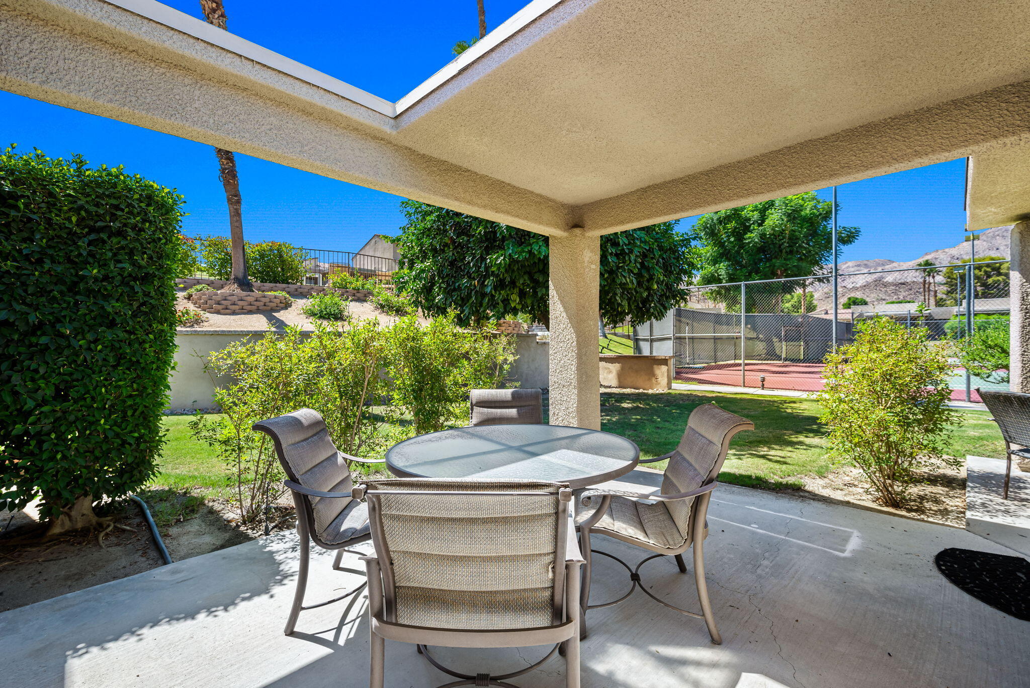 72499 Sandstone Lane Palm Desert, CA 92260 - Photo 21 of 53 a view of a patio with table and chairs potted plants with wooden floor and fence