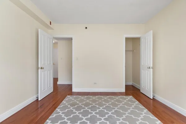 a view of an empty room with a window and wooden floor