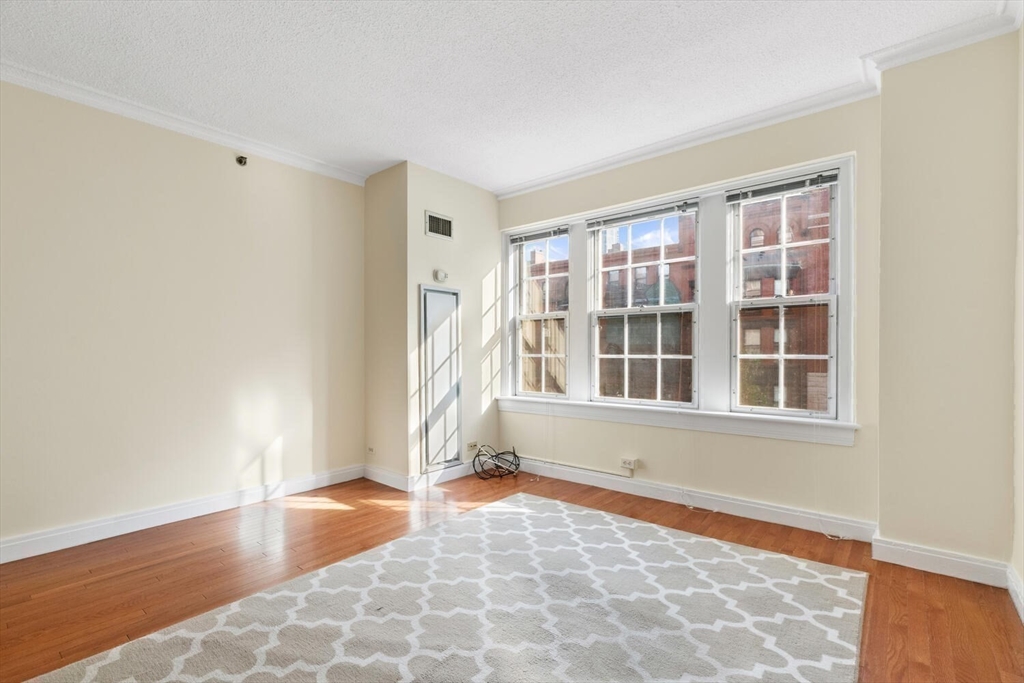 534 Beacon Street, Unit 302 Boston, MA 02215 - Photo 12 of 18 a view of an empty room with a window and wooden floor