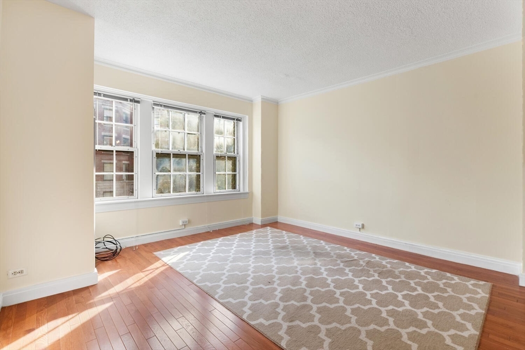 534 Beacon Street, Unit 302 Boston, MA 02215 - Photo 8 of 18 an empty room with wooden floor and windows