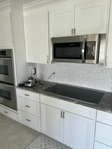 a kitchen with granite countertop white cabinets and white appliances