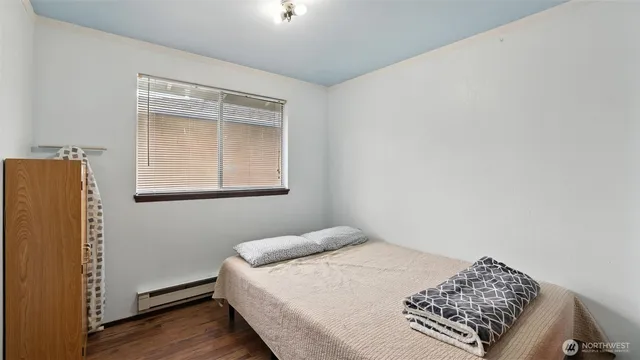 a bedroom with a bed and a window with wooden floor