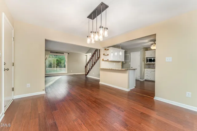 a view of a kitchen with wooden floor electronic appliances and stairs